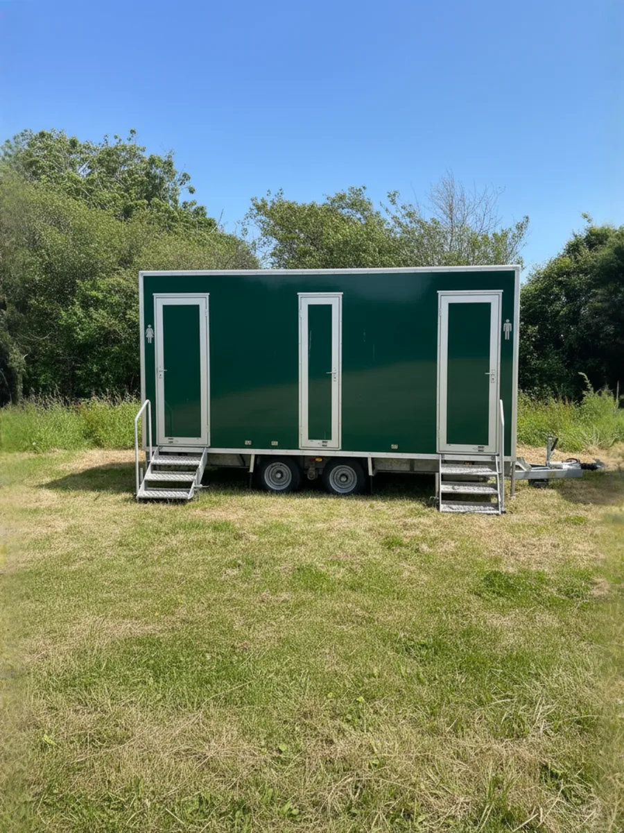 Green 2+1 mains luxury toilet trailer with twin entrance steps set up on grass
