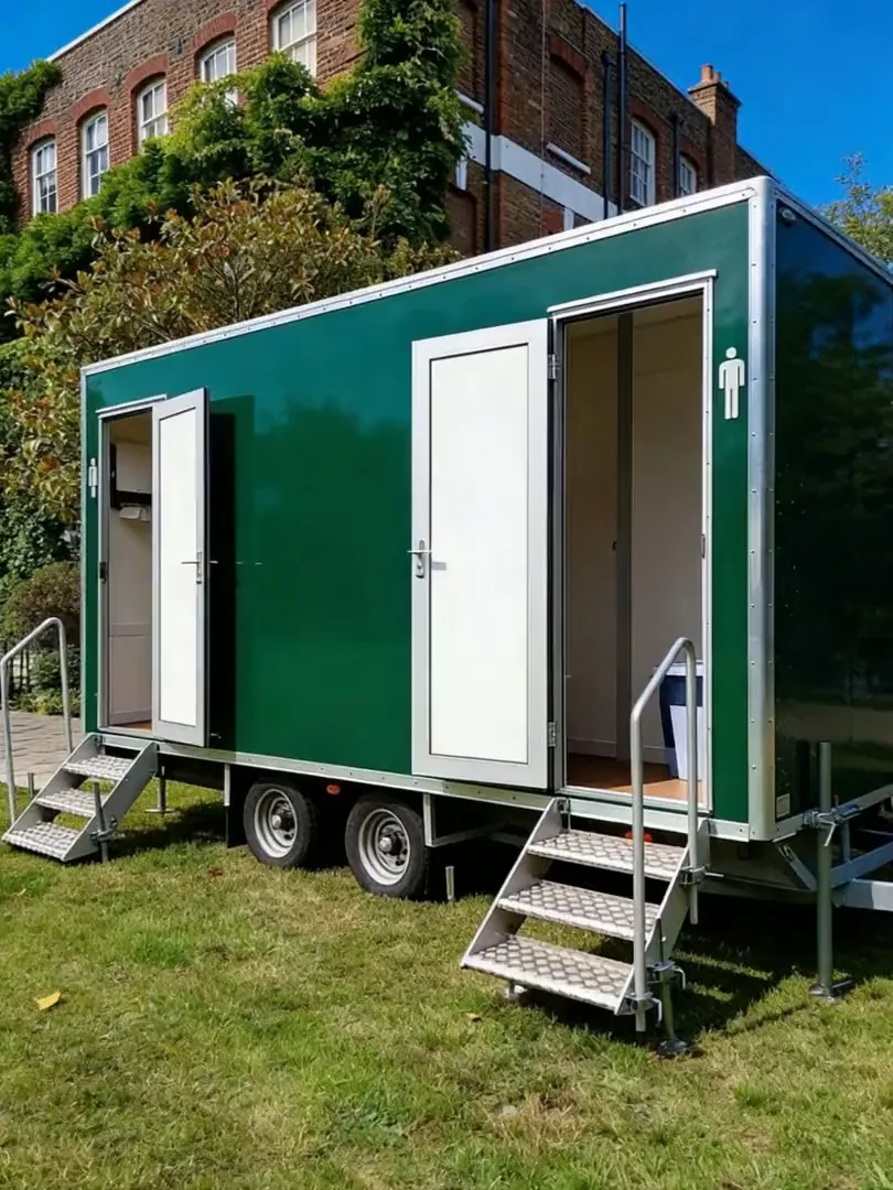 Green 2+1 mains luxury toilet trailer with entrance steps and doors open on grass